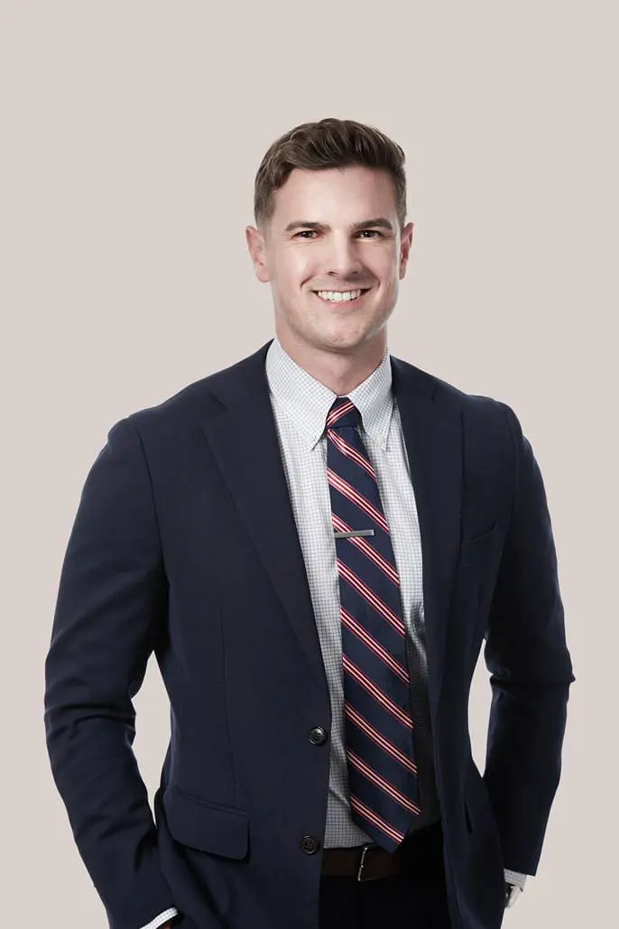 A man in a suit and striped tie, smiling, stands confidently against a neutral background—a classic style reminiscent of Janet Howard's timeless elegance.