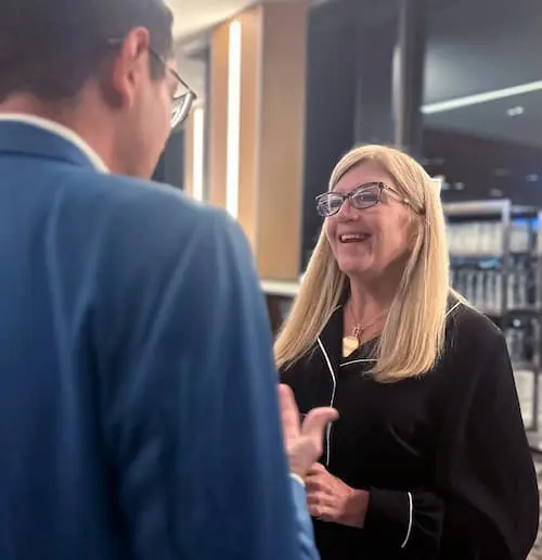 A woman with glasses smiles and speaks with a man, both in business attire, on the home page of a company's website.